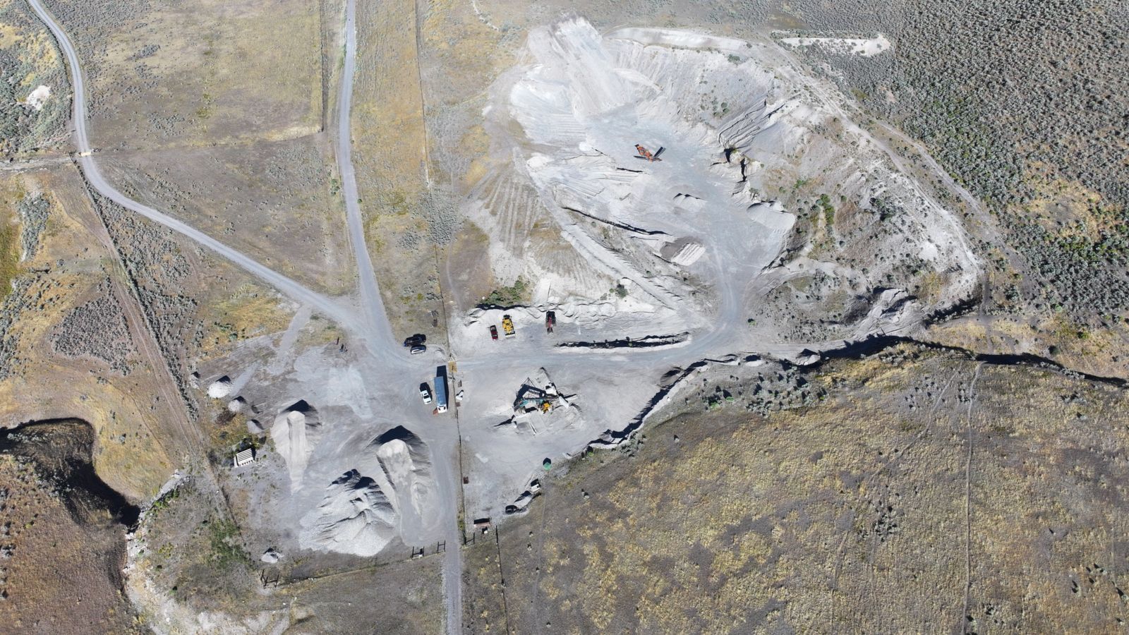 Aerial view of the J6 Rock gravel pit in Garland, Utah, with stockpiles, trucks and surrounding brown hills